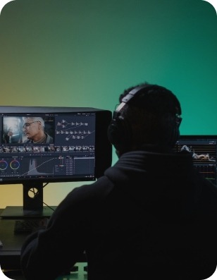 Man infront of computer editing videos in a timeline